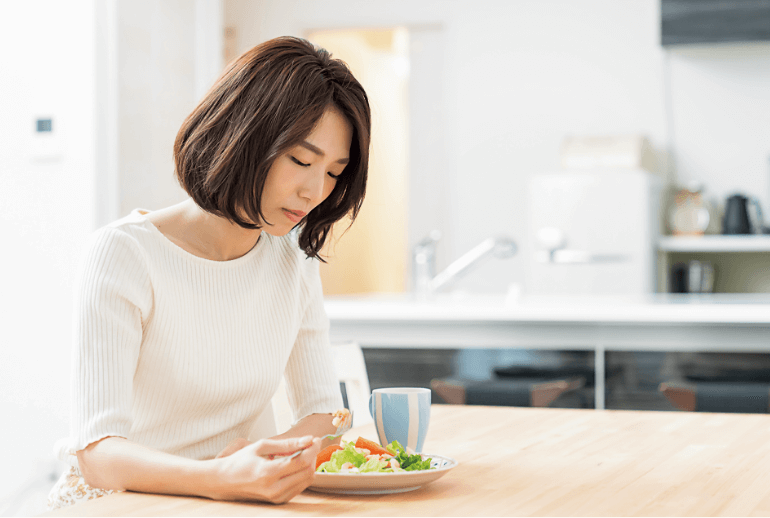 うつむき加減で食卓に座る女性