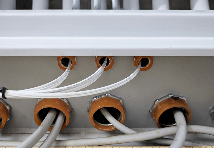 MDFから露出配管へと伸びる光回線と電話線の写真