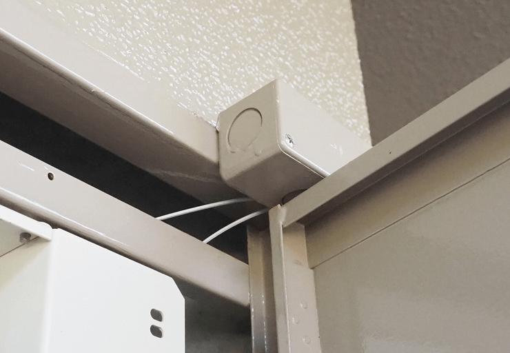 メーターボックスの上の方から光ケーブルを露出配管の中に通す様子