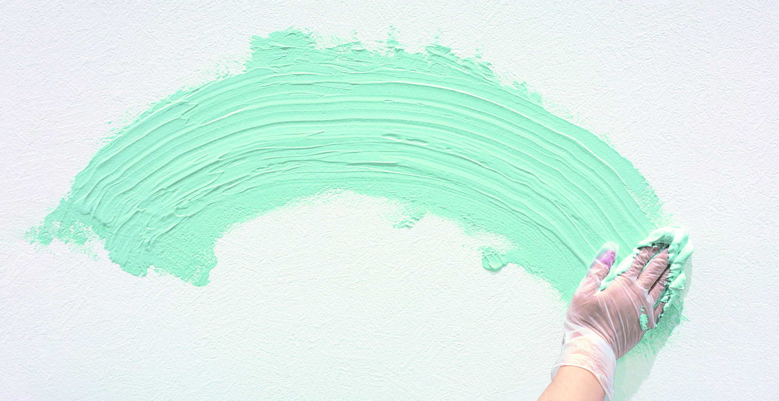 手で塗り広げられる黄緑色の漆喰風塗料