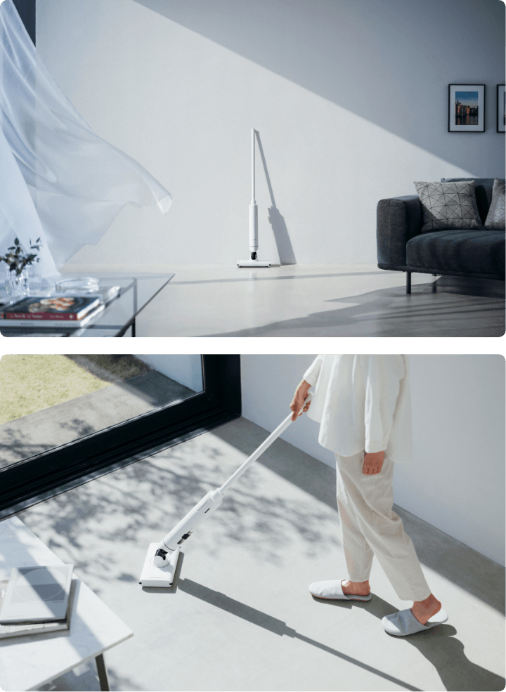 壁に立てかけられたBALMUDAのThe Cleaner Lite C02A-WH、床をBALMUDAのThe Cleaner Lite C02A-WHで掃除する女性