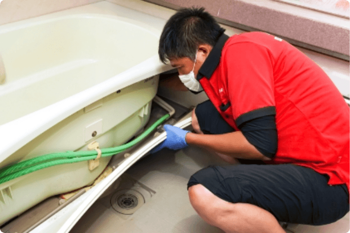 浴室をクリーニングする作業者