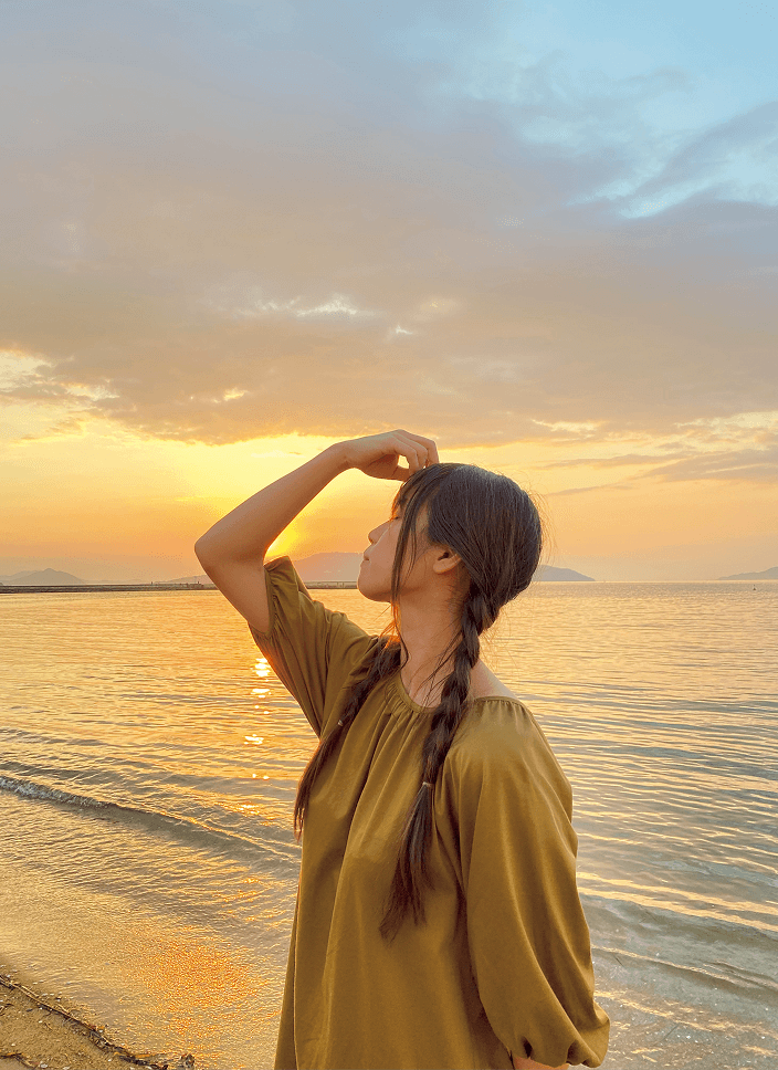 海を背景にしてポーズをとる女性