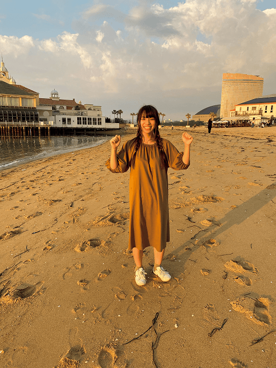 砂浜で笑ってポーズをとる女性を真正面から映したNG写真