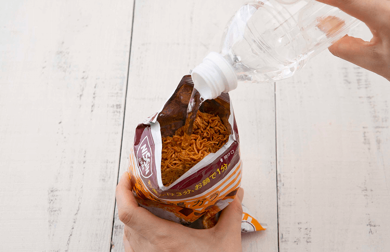 袋麺の袋に直接水を注ぐ様子