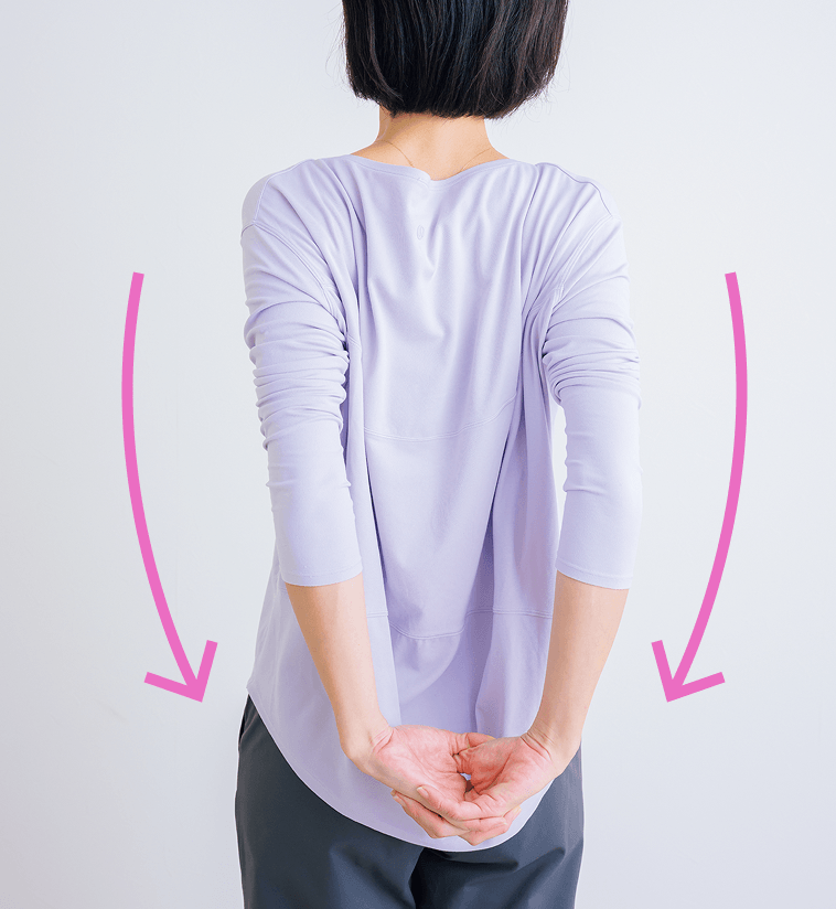 後ろで手を組みポーズをとる先生