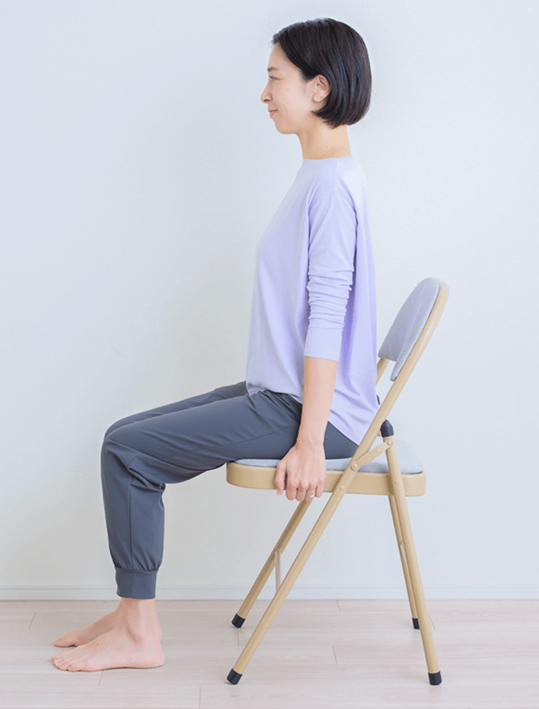 両足を揃え正しい姿勢で椅子に座り、座面やふちを両手でつかむ先生
