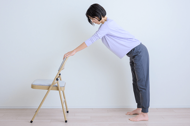 足を腰幅に開き太ももやふくらはぎの裏を伸ばし呼吸する先生