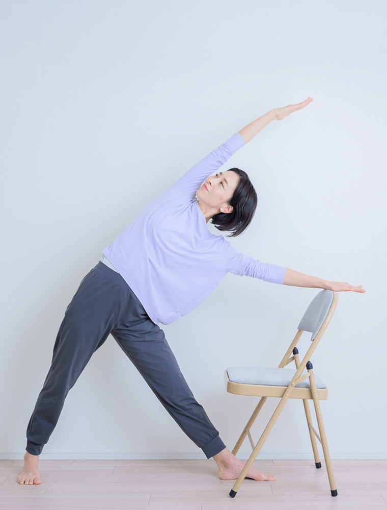 足を開いて片方の手を椅子の背もたれに添える先生