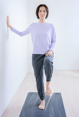 壁に片手を添えて片足を上げる先生