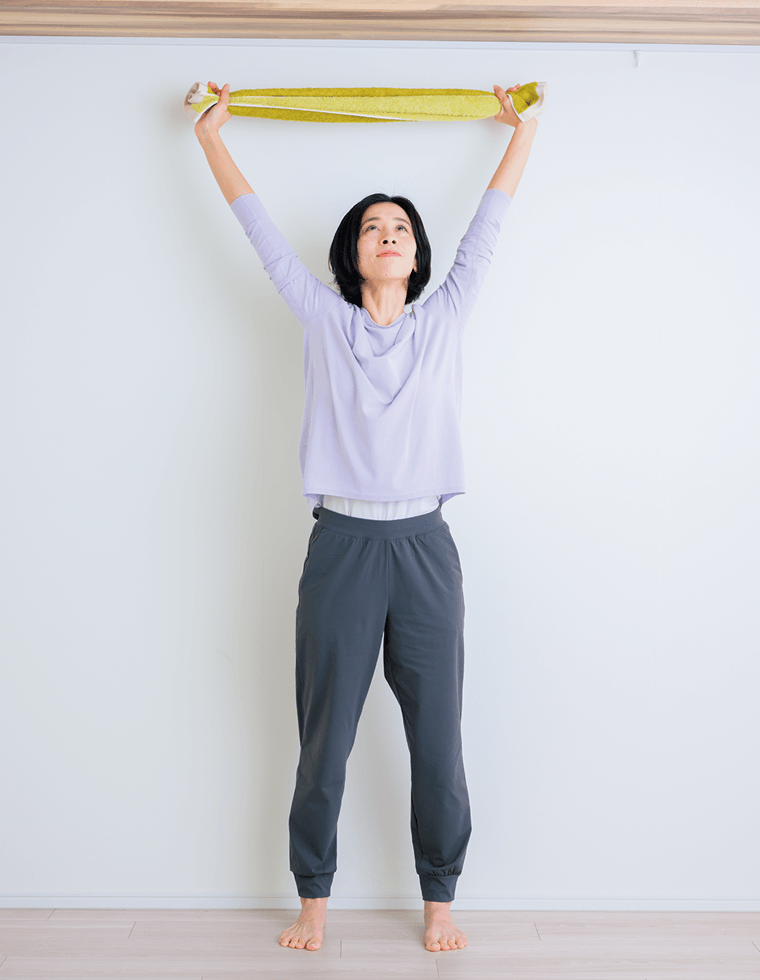 両手でタオルを持って腕を上げる先生