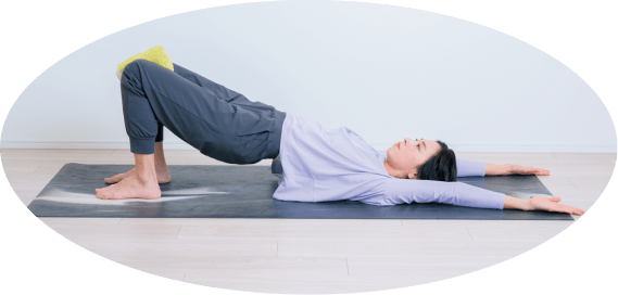 タオルを膝に挟んだ姿勢で両手を上に伸ばす先生