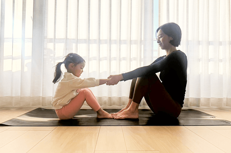 体育座りで向かい合って両手をつなぐ親子