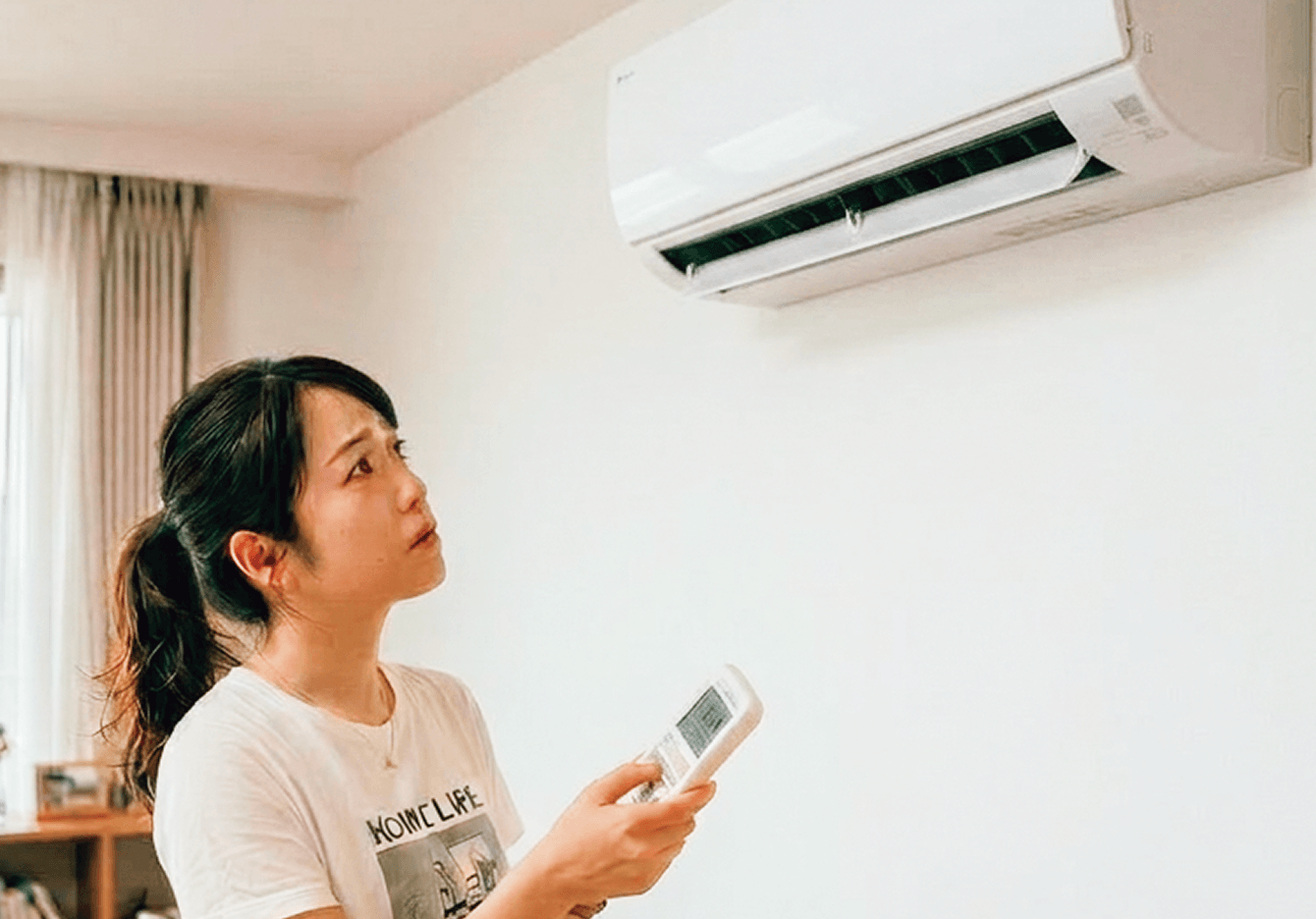 エアコンにリモコンを向ける女性