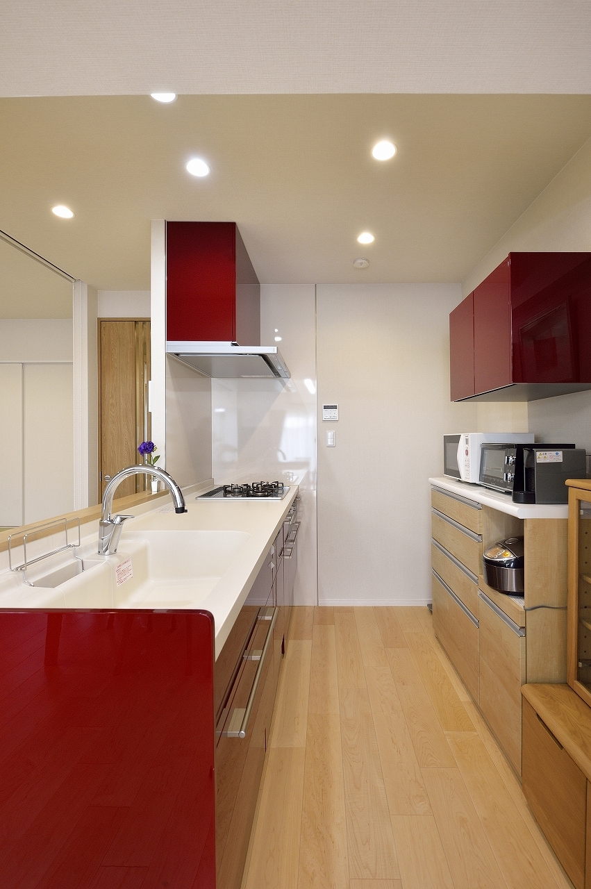 キッチン　ー　対面型にリフォームしたキッチンには、落ち着いたレッドトーンが映える深型食洗器搭載のシステムキッチンを設置。配管スペースや腰壁の厚みとの兼ね合いがよいものを厳選しました。