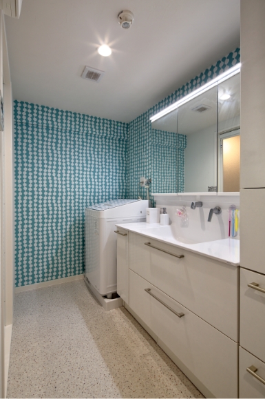 洗面所の壁紙：白を基調とした空間。1面は青地に白い水玉模様のクロス。